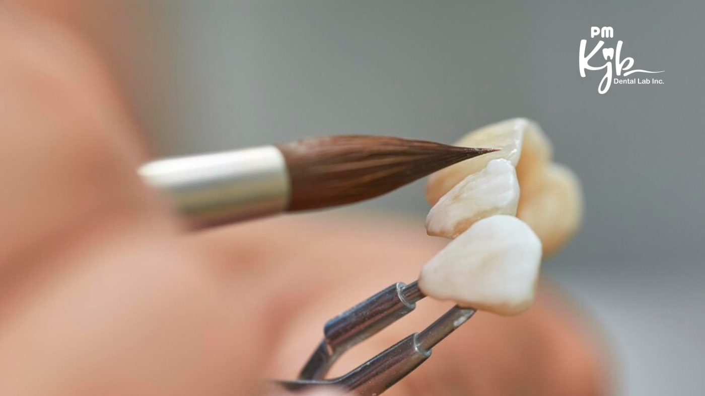 Close-up of a dental technician applying ceramic layers to PFM crowns using a brush